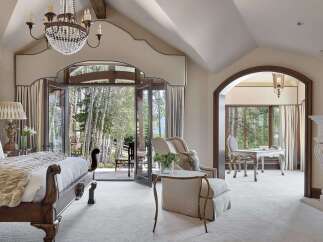 Experience luxurious mountain living in this stunning bedroom featuring a grand crystal chandelier and a cozy seating area.