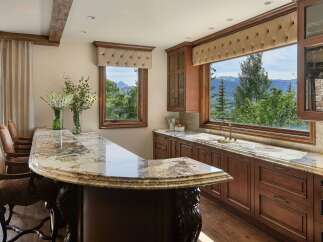 Experience luxury living with this stunning custom bar area, featuring a granite countertop and rich wood cabinetry.