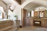 Experience rustic luxury in this stunning bathroom, featuring a deep soaking tub with elegant stone steps and a unique taxidermy antelope mount.