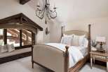 Experience rustic elegance in this charming bedroom, featuring a luxurious four-poster bed adorned with plush pillows and crisp white linens.