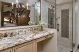 Indulge in luxury with this stunning bathroom featuring a granite countertop vanity and a spacious walk-in shower.