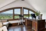 This stunning home office boasts breathtaking mountain views through expansive arched windows, creating an inspiring workspace.