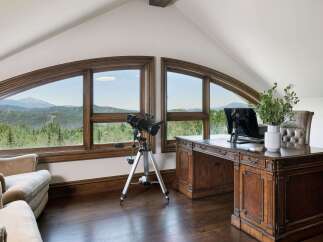 This stunning home office boasts breathtaking mountain views through expansive arched windows, creating an inspiring workspace.