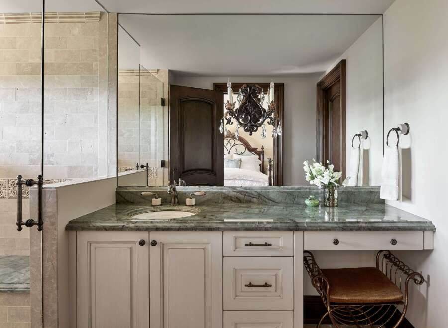 Experience luxury in this master bathroom featuring a stunning green marble vanity with a vessel sink and elegant bronze fixtures.