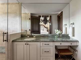Experience luxury in this master bathroom featuring a stunning green marble vanity with a vessel sink and elegant bronze fixtures.