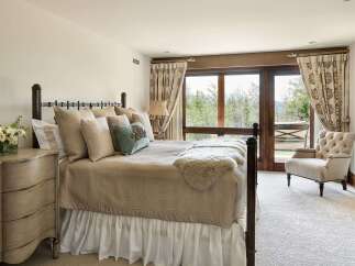 Experience serene mountain living in this charming bedroom, featuring a plush queen-size bed adorned with textured linens and decorative pillows.
