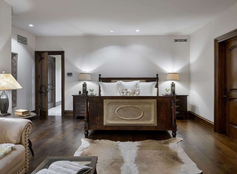 Experience luxurious comfort in this master bedroom, featuring a grand dark wood bed with an ornate headboard and plush white bedding.