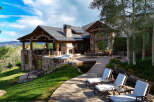 Experience luxury mountain living in this stunning estate, featuring a spacious outdoor living area with a hot tub and a serene water feature.
