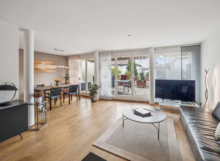 This spacious living and dining area boasts a modern aesthetic with a sleek black sideboard and a large black leather sofa.