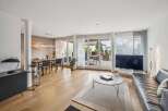 This spacious living and dining area boasts a modern aesthetic with a sleek black sideboard and a large black leather sofa.