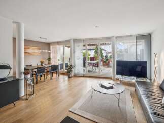 This spacious living and dining area boasts a modern aesthetic with a sleek black sideboard and a large black leather sofa.