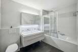This modern bathroom features a sleek floating vanity with a double sink, illuminated by a stylish mirror with integrated lighting.