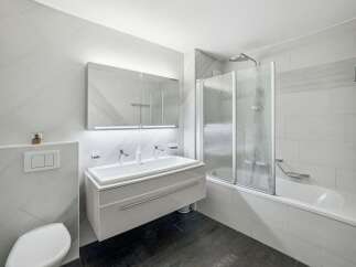 This modern bathroom features a sleek floating vanity with a double sink, illuminated by a stylish mirror with integrated lighting.