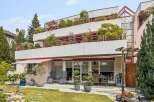 Experience modern living in this multi-level property featuring expansive balconies adorned with lush greenery and vibrant flowers.