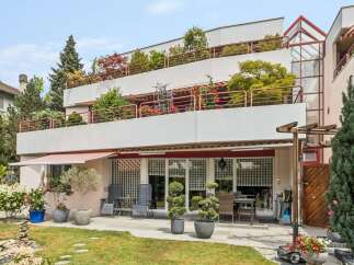 Experience modern living in this multi-level property featuring expansive balconies adorned with lush greenery and vibrant flowers.
