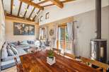 Experience rustic charm in this spacious living and dining area, featuring a large sectional sofa, a stunning wooden dining table, and a cozy wood-burning stove.