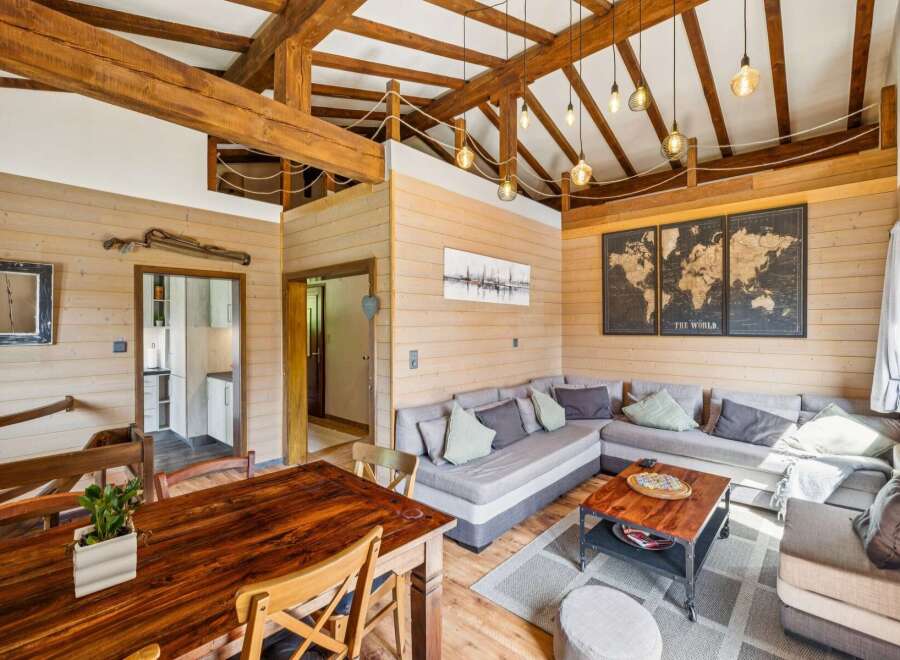 Experience rustic charm in this spacious living area, featuring exposed wooden beams and warm wood-paneled walls.