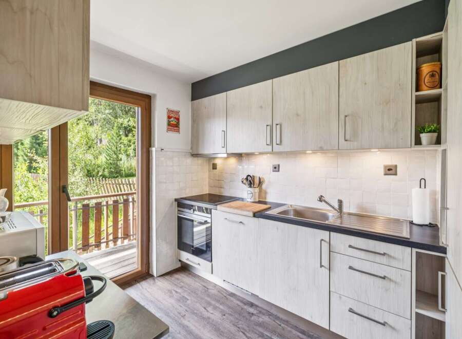 Discover this charming kitchen featuring light wood cabinetry and a sleek dark countertop.