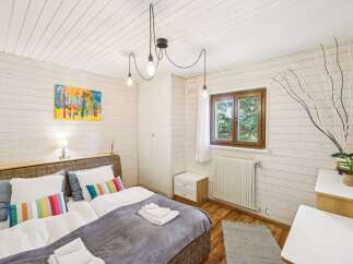 Experience cozy comfort in this charming bedroom, featuring a plush bed adorned with colorful striped accent pillows.