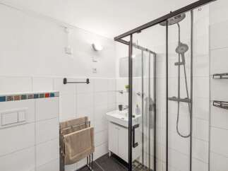 This modern bathroom features a sleek glass-enclosed shower with a rainfall showerhead, perfect for a spa-like experience.