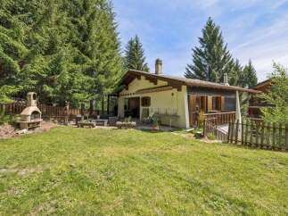 Enjoy outdoor living in this charming property featuring a spacious green lawn and a built-in barbecue area, perfect for summer gatherings.