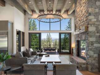 Experience luxury mountain living in this stunning great room, featuring a grand stone fireplace and soaring beamed ceilings.
