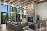 Experience luxury mountain living in this stunning great room, featuring a grand stone fireplace and expansive windows that frame breathtaking forest and mountain views.