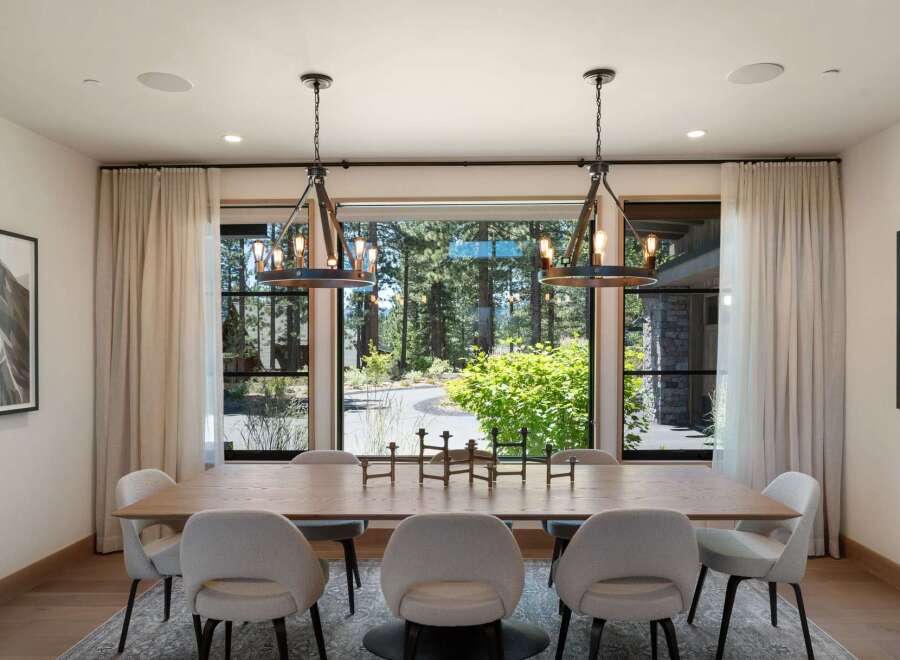 Experience elegant dining in this spacious room, featuring a large wooden table surrounded by plush upholstered chairs.