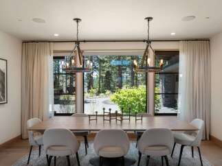 Experience elegant dining in this spacious room, featuring a large wooden table surrounded by plush upholstered chairs.