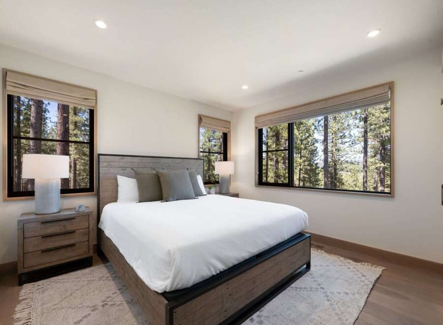 Experience serene living in this beautifully appointed bedroom, featuring a rustic wooden bed frame and plush bedding.