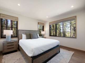 Experience serene living in this beautifully appointed bedroom, featuring a rustic wooden bed frame and plush bedding.