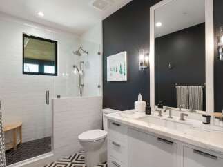 Experience modern luxury in this stunning bathroom, featuring a sleek glass-enclosed shower with subway tile and a chic vanity with a marble countertop.
