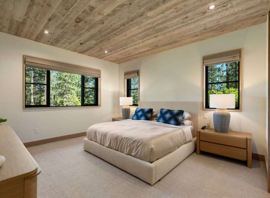 Experience serene living in this beautifully appointed bedroom, featuring a luxurious bed and a rustic wood-planked ceiling.