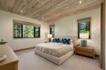Experience serene living in this beautifully appointed bedroom, featuring a luxurious bed and a rustic wood-planked ceiling.