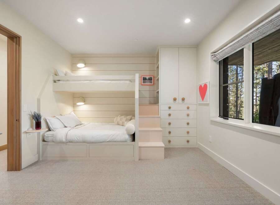 This charming bedroom features a space-saving bunk bed with integrated storage, perfect for maximizing room functionality.