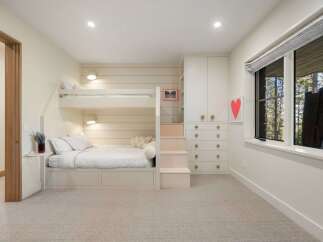 This charming bedroom features a space-saving bunk bed with integrated storage, perfect for maximizing room functionality.