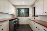 This modern laundry room boasts ample storage with white shaker cabinets and rich walnut countertops.