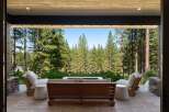 Experience seamless indoor-outdoor living with this stunning patio, featuring comfortable seating and a modern fire pit, perfect for enjoying the breathtaking forest views.