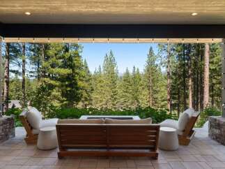 Experience seamless indoor-outdoor living with this stunning patio, featuring comfortable seating and a modern fire pit, perfect for enjoying the breathtaking forest views.
