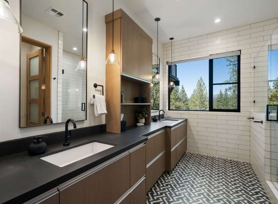 Experience modern luxury in this stunning bathroom featuring a dual vanity with sleek black countertops and rich wood cabinetry.