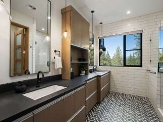 Experience modern luxury in this stunning bathroom featuring a dual vanity with sleek black countertops and rich wood cabinetry.