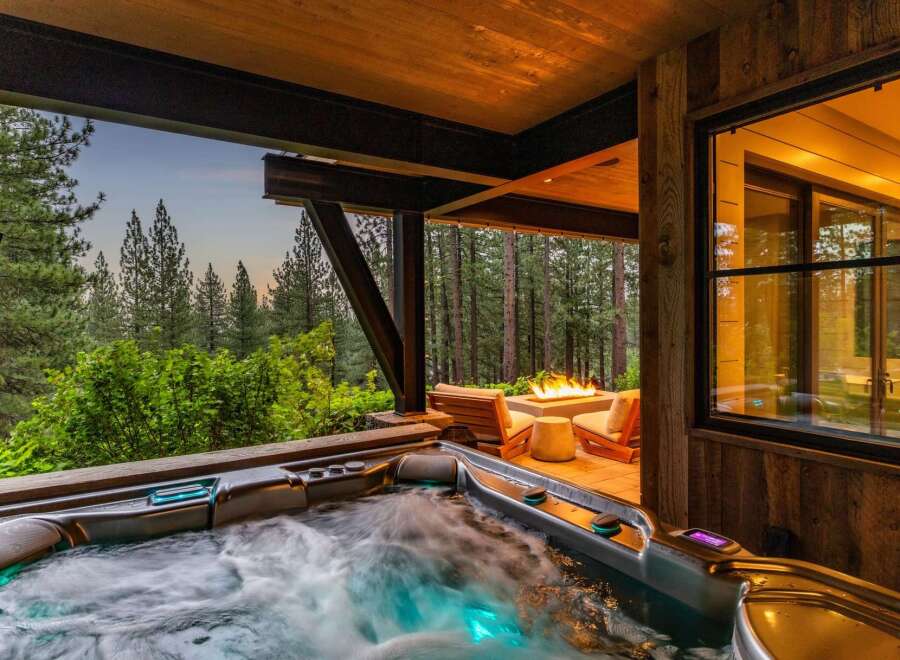 Indulge in ultimate relaxation with this luxurious outdoor living space, featuring a steaming hot tub perfect for unwinding.