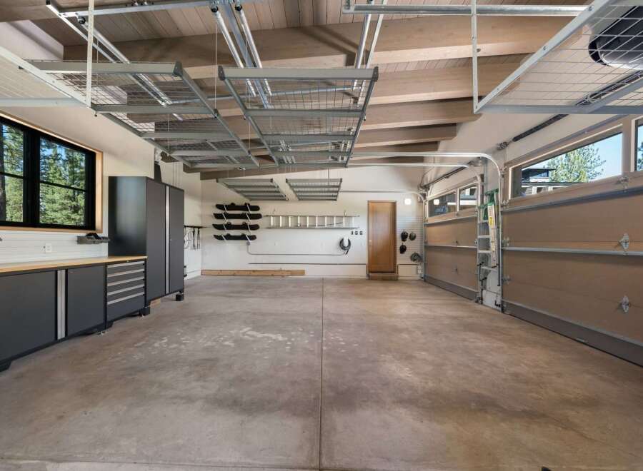 This spacious garage offers ample storage solutions with overhead shelving and wall-mounted racks, perfect for organizing tools and equipment.
