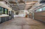 This spacious garage offers ample storage solutions with overhead shelving and wall-mounted racks, perfect for organizing tools and equipment.