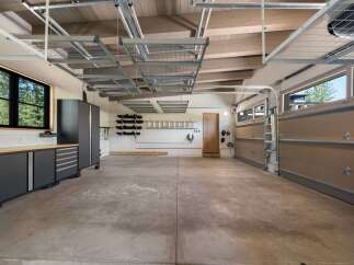 This spacious garage offers ample storage solutions with overhead shelving and wall-mounted racks, perfect for organizing tools and equipment.