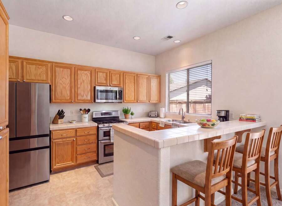 Discover this charming kitchen featuring warm wood cabinetry and a convenient breakfast bar perfect for casual dining.
