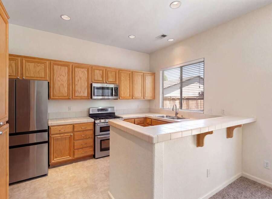 This spacious kitchen features beautiful light wood cabinetry, a stainless steel refrigerator, and a double oven gas range.