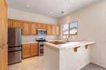 This spacious kitchen features beautiful light wood cabinetry, a stainless steel refrigerator, and a double oven gas range.