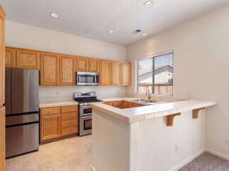 This spacious kitchen features beautiful light wood cabinetry, a stainless steel refrigerator, and a double oven gas range.