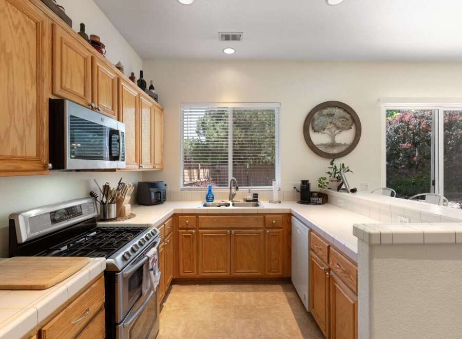 This charming kitchen features warm oak cabinetry and a spacious double sink beneath a large window, perfect for natural light.
